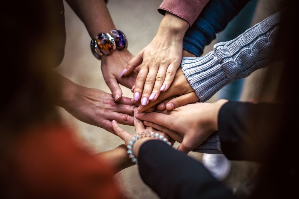 Plusieurs mains empilées l'une sur l'autre, symbolisant l'unité, le soutien et le travail d'équipe.